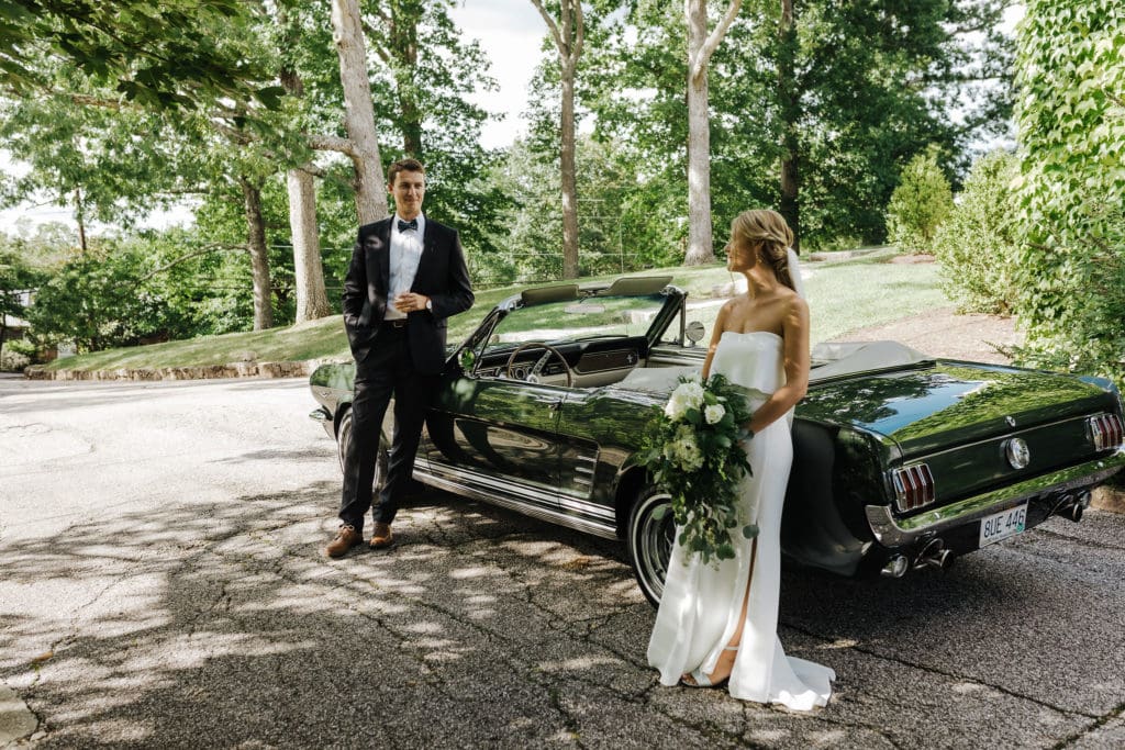 Photo ops galore: bride and groom pose with vintage car.
