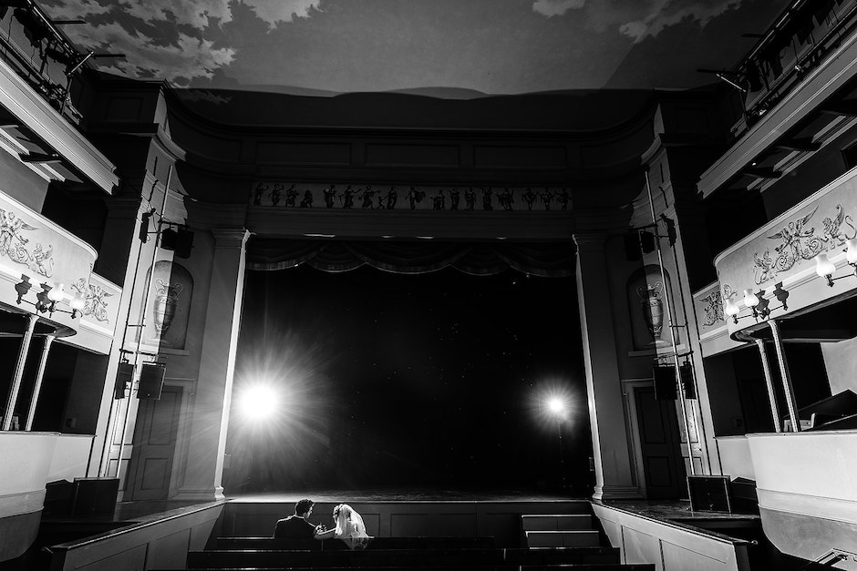 Dark wedding venue with bride and groom sitting in theater.