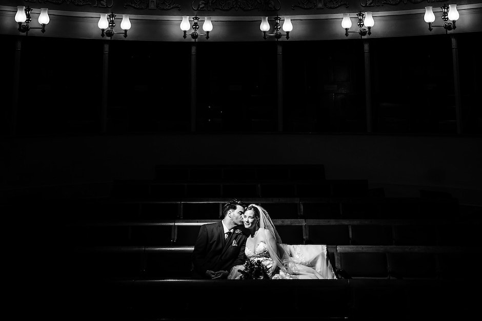 black and white of bride and groom sitting in theater seats where they got married.