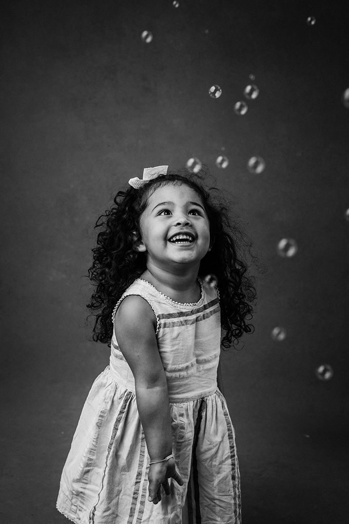 girl looking at bubbles for portraits tips for getting natural smiles from kids