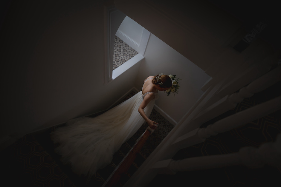 chiaroscuro image of bride going down stairs