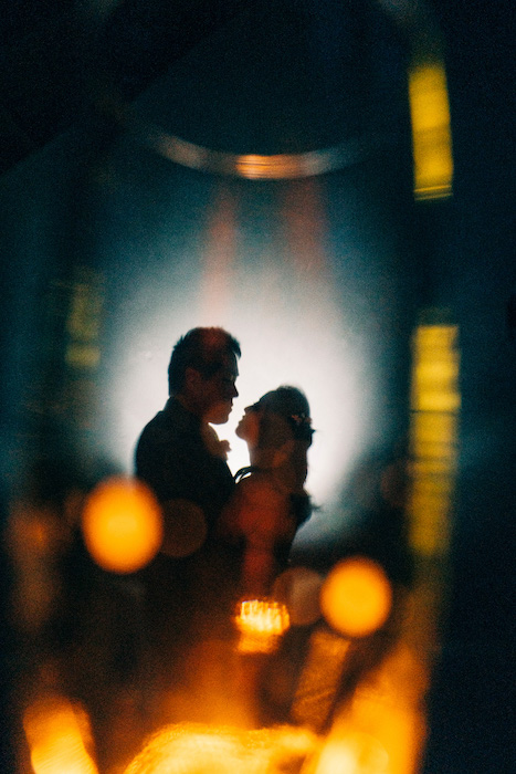 bride and groom wedding portrait in reflection of wine glass.