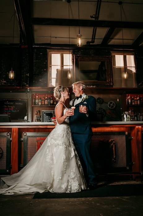 Older bride and groom leaning against the bar.