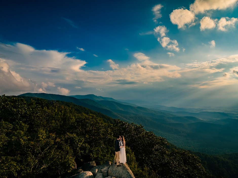 couple on top of mountain overlooking trees