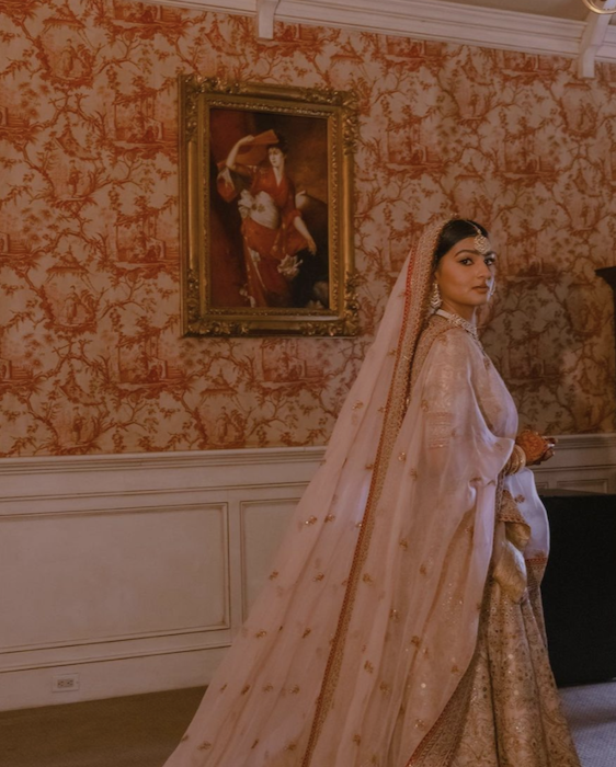 une mariée indienne contre une chambre tapissée