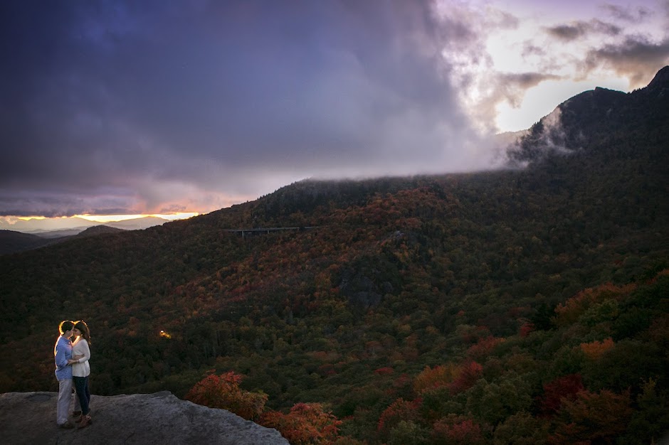 couple embraces on rock overlooking forests.