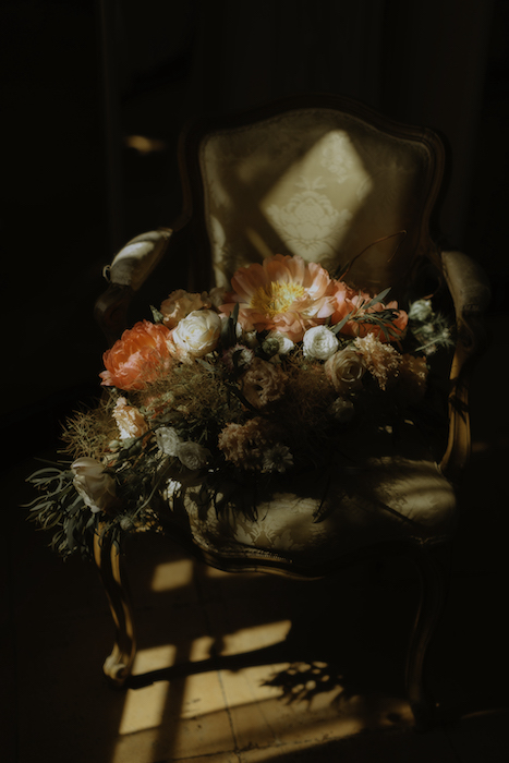 wedding details of florals on chair in light and shadow.
