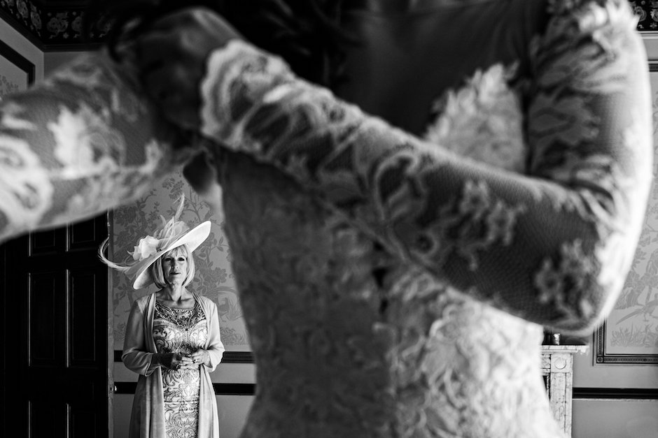 mom watches her daughter get dressed for wedding.
