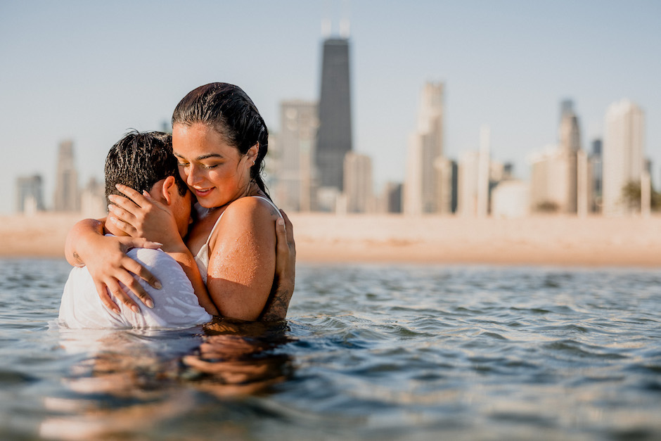 Couple in water with city backdrop.