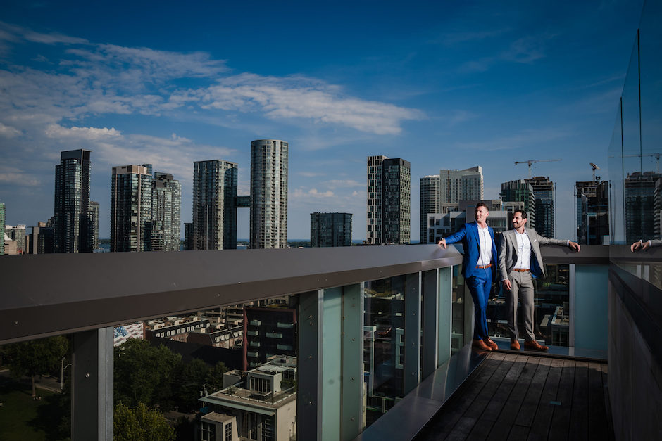 two grooms atop building overlooking city.