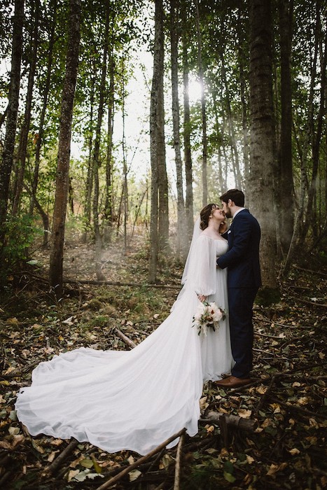 tender photo moment between bride and groom in the woods.