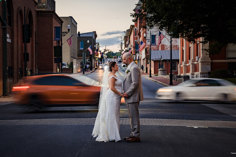 Bride and groom portrait in front of speeding cars.