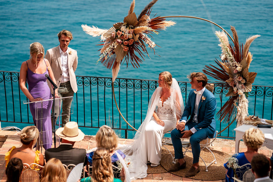 bride and groom sitting in front of sea.