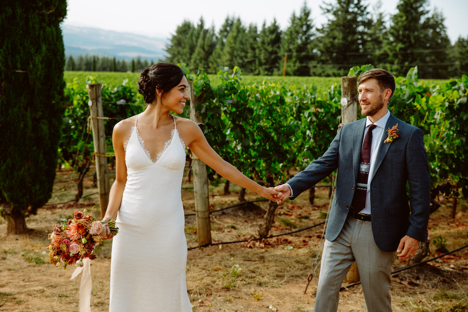 couple holds hands in field