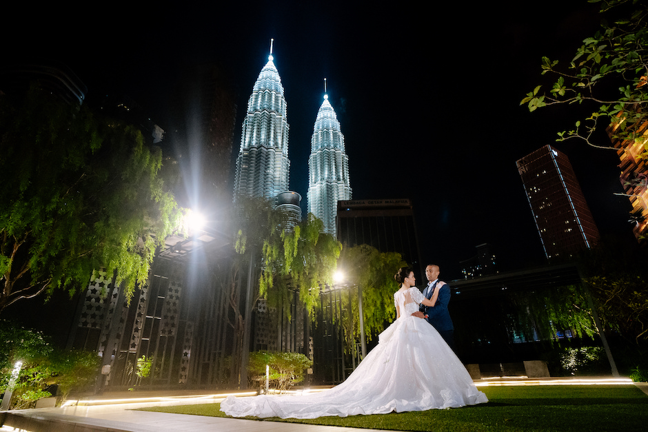 bride and groom in front of iconic towers in Malaysia